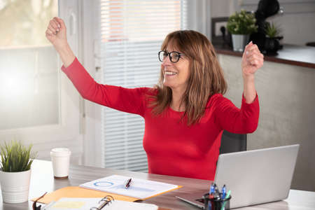 Mature businesswoman with arms up; business successの写真素材