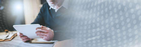 Senior man using his tablet at home; panoramic banner