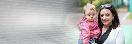 Portrait of happy young mother with her baby girl in a playground, outside; panoramic bannerの写真素材