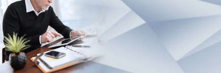 Senior businessman working on digital tablet at office; panoramic bannerの写真素材