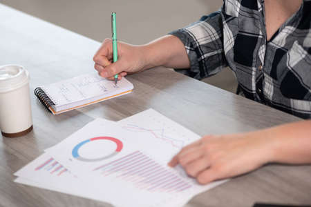Businesswoman analyzing marketing data and taking notesの写真素材