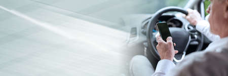 Man using his mobile phone while driving; panoramic bannerの写真素材