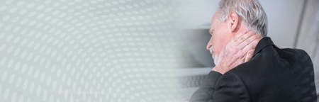 Senior businessman suffering from neck pain; panoramic bannerの写真素材