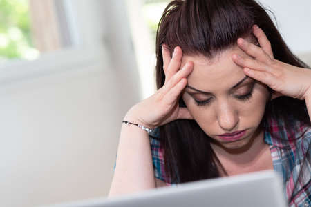 Overworked young businesswoman sitting in front of laptop