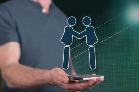 Business partner concept above a smartphone held by a man in backgroundの写真素材