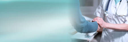Female doctor holding patient hand for encouragement; panoramic bannerの写真素材