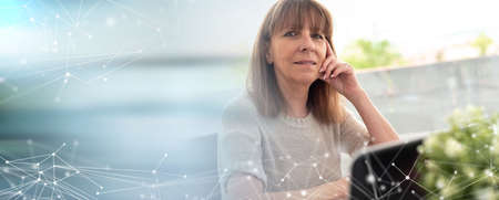Portrait of mature businesswoman sitting at office; panoramic bannerの写真素材