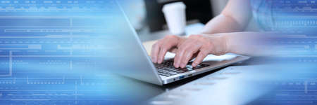 Female hands working on laptop in office; panoramic banner