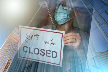 Store owner hanging sorry we're closed sign on window; multiple exposure