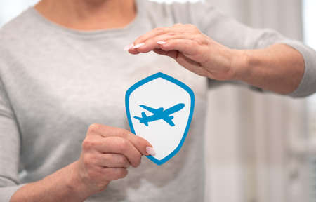 Concept of flight insurance with paper shield held by female handの写真素材