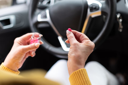 Woman sitting in car and taking pills before drivingの写真素材