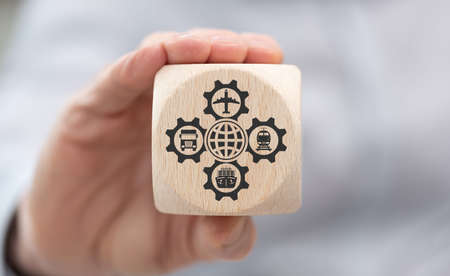 Hand holding a wooden cube with symbol of global transportation conceptの写真素材