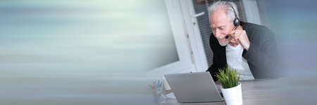 Portrait of senior male helpline operator in headset; panoramic banner