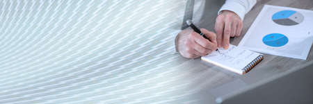Businessman analyzing marketing data and taking notes; panoramic banner