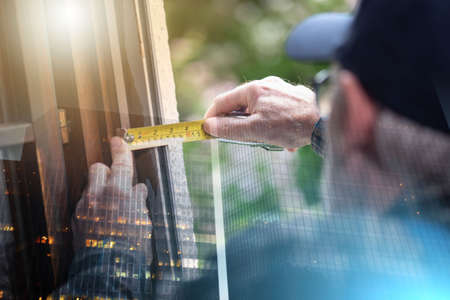 Senior repairman taking measures with tape measure; multiple exposureの写真素材