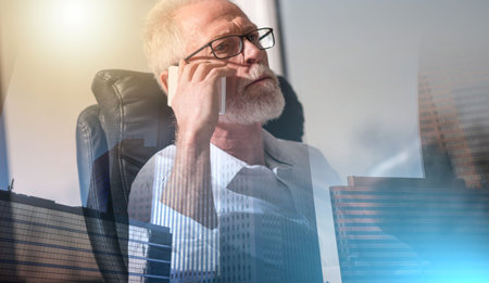 Portrait of bearded senior businessman talking on mobile phone in office, hard light; multiple exposureの写真素材