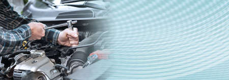 Hands of car mechanic repairing a car engine; panoramic banner