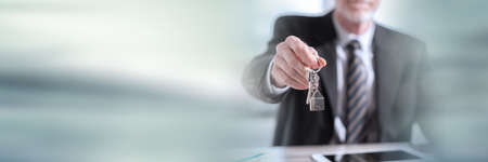 Real estate agent offering house keys; panoramic bannerの写真素材