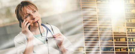 Female doctor talking on mobile phone in medical office; multiple exposureの写真素材