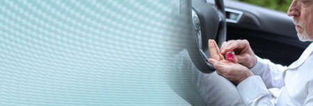 Man sitting in car and taking pills before driving; panoramic banner