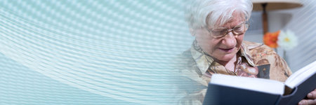 Old woman reading a book at home; panoramic bannerの写真素材