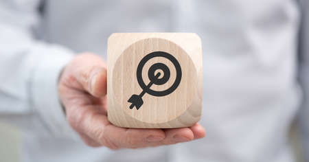 Hand holding a wooden cube with symbol of target marketing concept