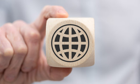 Hand holding a wooden cube with symbol of global transportation conceptの写真素材