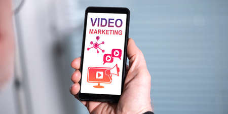 Hand holding a smartphone with video marketing conceptの写真素材