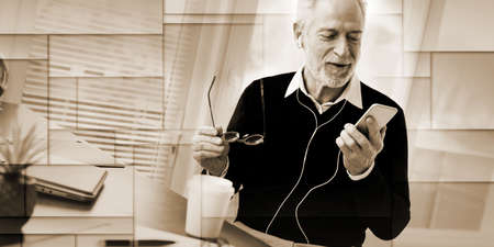 Senior businessman using earphones during conversation on mobile phone, geometric patternの写真素材