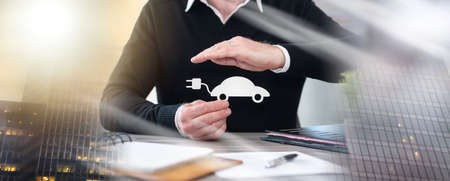 Insurer protecting an electric car with his hand; multiple exposureの写真素材