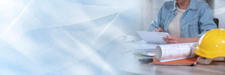 Female architect working on new construction project with digital tablet; panoramic banner
