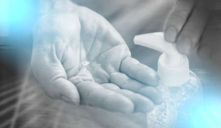 Hand pressing on sanitizer alcohol gel bottle; prevention of virus and bacteria infection; light effectの写真素材