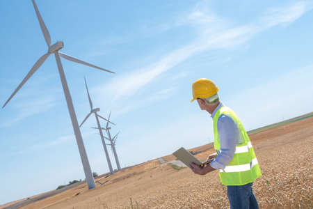 Electrical engineer using laptop for wind turbine inspection