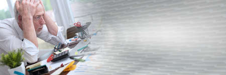 Overworked senior businessman sitting at a messy desk; panoramic bannerの写真素材