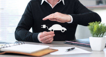 Insurer protecting an electric car with his handの写真素材