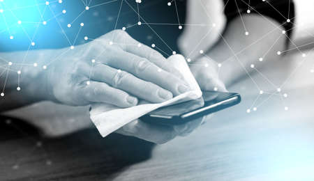 Woman disinfecting smartphone with antibacterial wipe; prevention of virus and bacteria infection;...