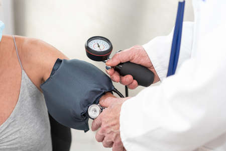 Doctor measuring blood pressure of a female patient