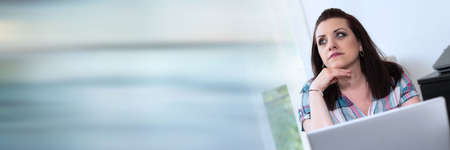 Portrait of young thoughtful businesswoman looking up; panoramic banner