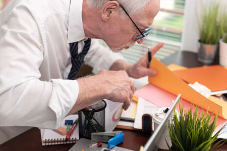 Disorganized businessman looking for documents on his messy desk