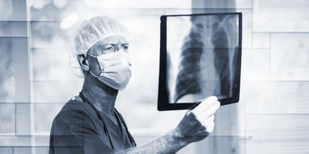 Surgeon wearing a medical face mask and examining lungs x-ray during virus outbreak, geometric patternの写真素材
