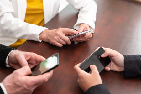 Group of people using and looking at mobile phone togetherの写真素材