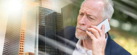 Mature man using his mobile phone outdoors, light effect; multiple exposureの写真素材