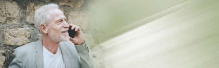 Mature man using his mobile phone outdoors; panoramic banner