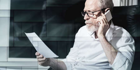 Bearded senior businessman talking on mobile phone in office, hard light, geometric pattern