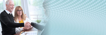 Real estate agent giving handshake to happy senior couple after successful agreement; panoramic bannerの写真素材