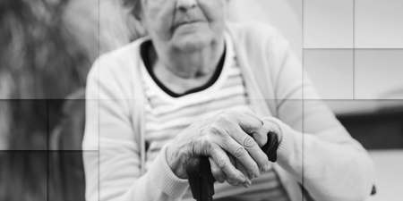 old woman sitting with her hands on a cane, geometric pattern