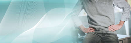 Businessman with hands on hips sitting on his desk; panoramic banner