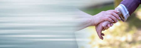 Concept of elderly support; young and old holding hands; panoramic banner