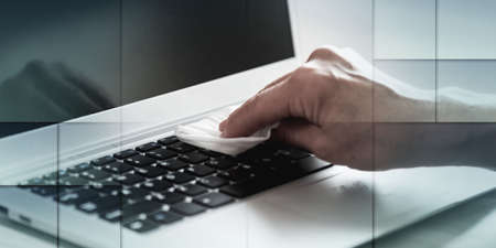 woman disinfecting laptop keyboard with antibacterial wipe; prevention of virus and bacteria...