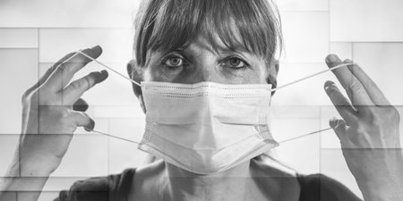 Portrait of mature woman putting on a medical mask on her face, geometric patternの写真素材
